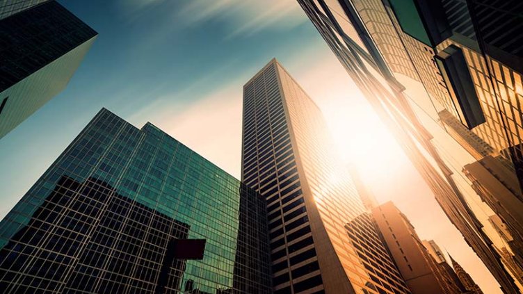 Sun shine behind large buildings